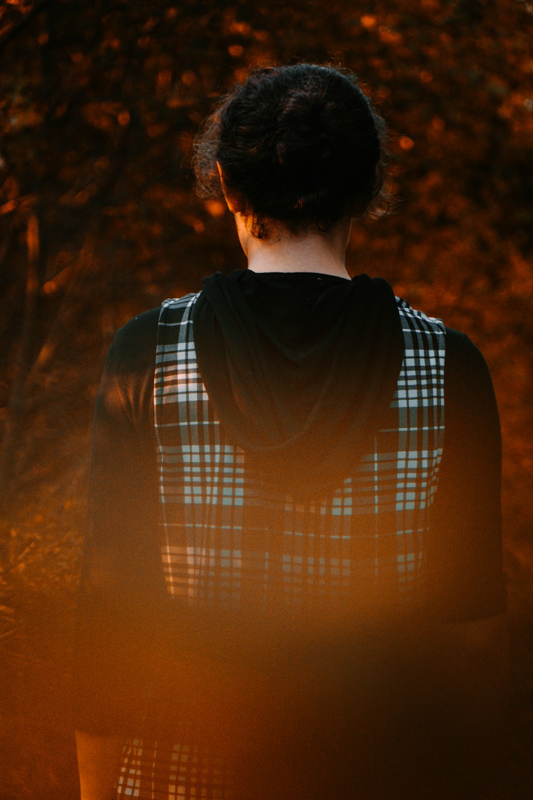 man in white and blue plaid shirt standing near trees during sunset