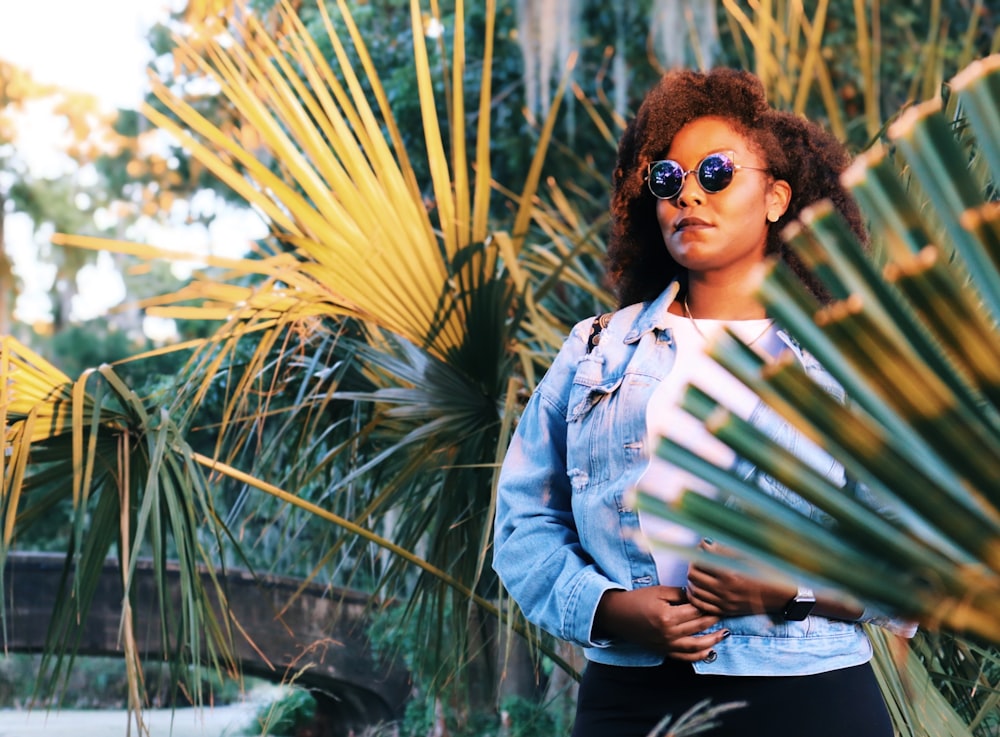 Femme en veste en jean bleue et lunettes de soleil noires