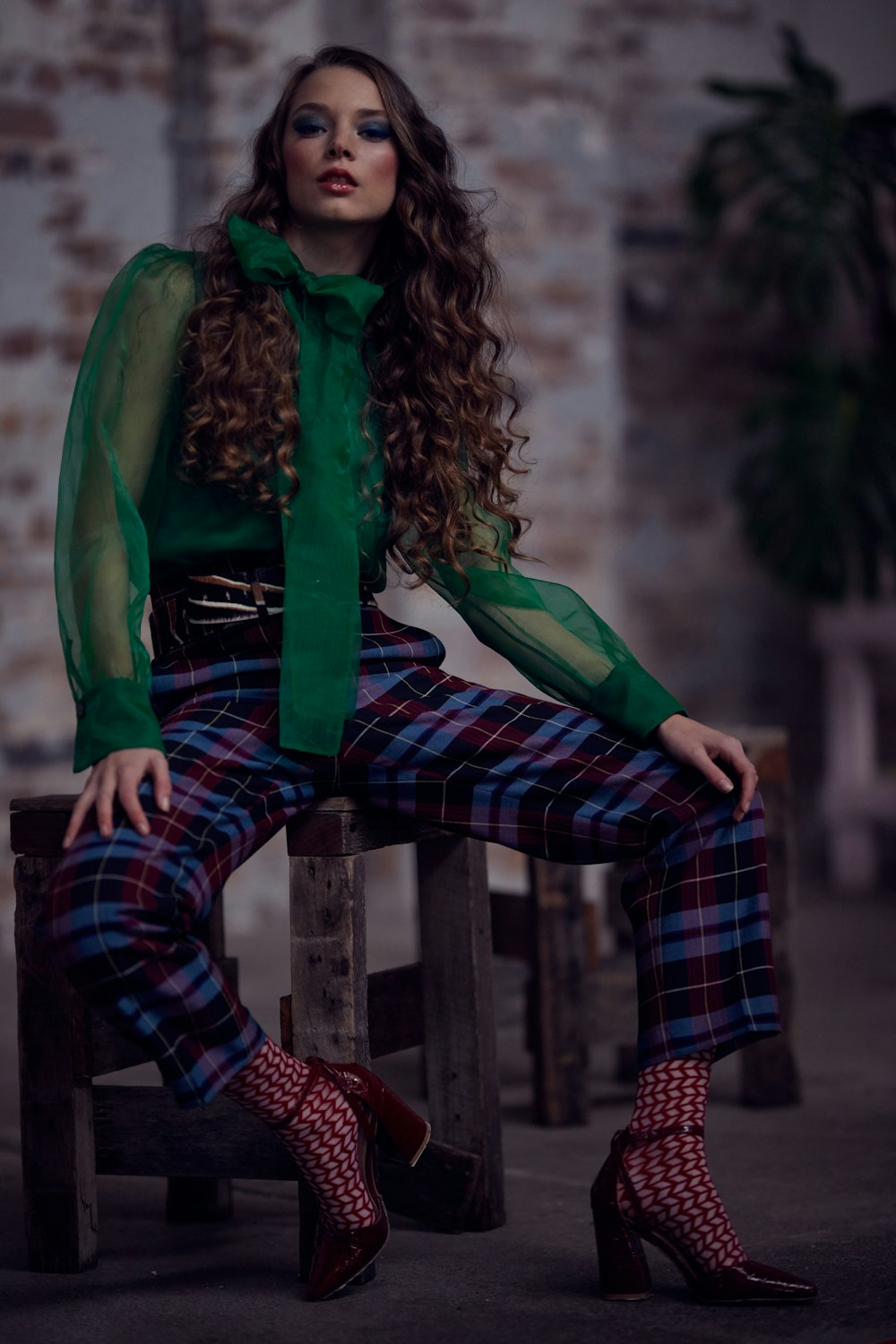 woman in green leather jacket and black and red plaid pants sitting on brown wooden bench
