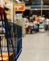 A blue metal shopping cart in a blurred grocery store aisle