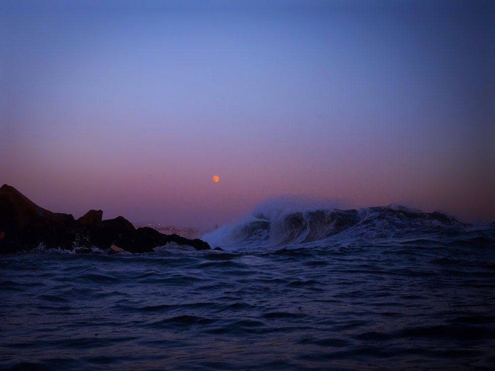 ocean waves crashing on rocky shore during sunset