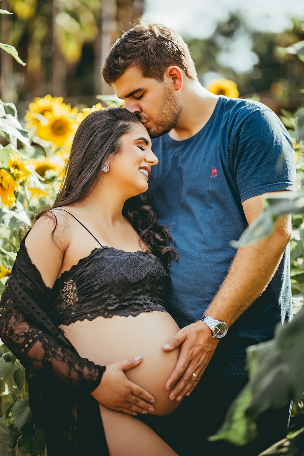 man in blue crew neck t-shirt kissing woman in black floral lace spaghetti strap top