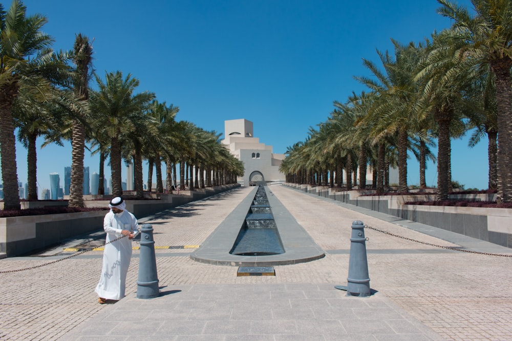 woman in white dress standing on gray concrete pathway during daytime