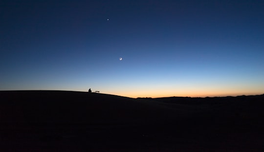 silhouette of person standing on hill during sunset in Merzouga Morocco