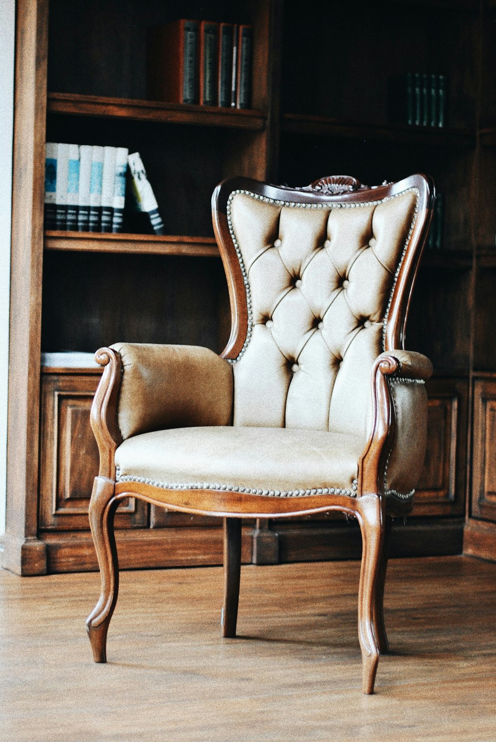 brown wooden framed beige padded armchair