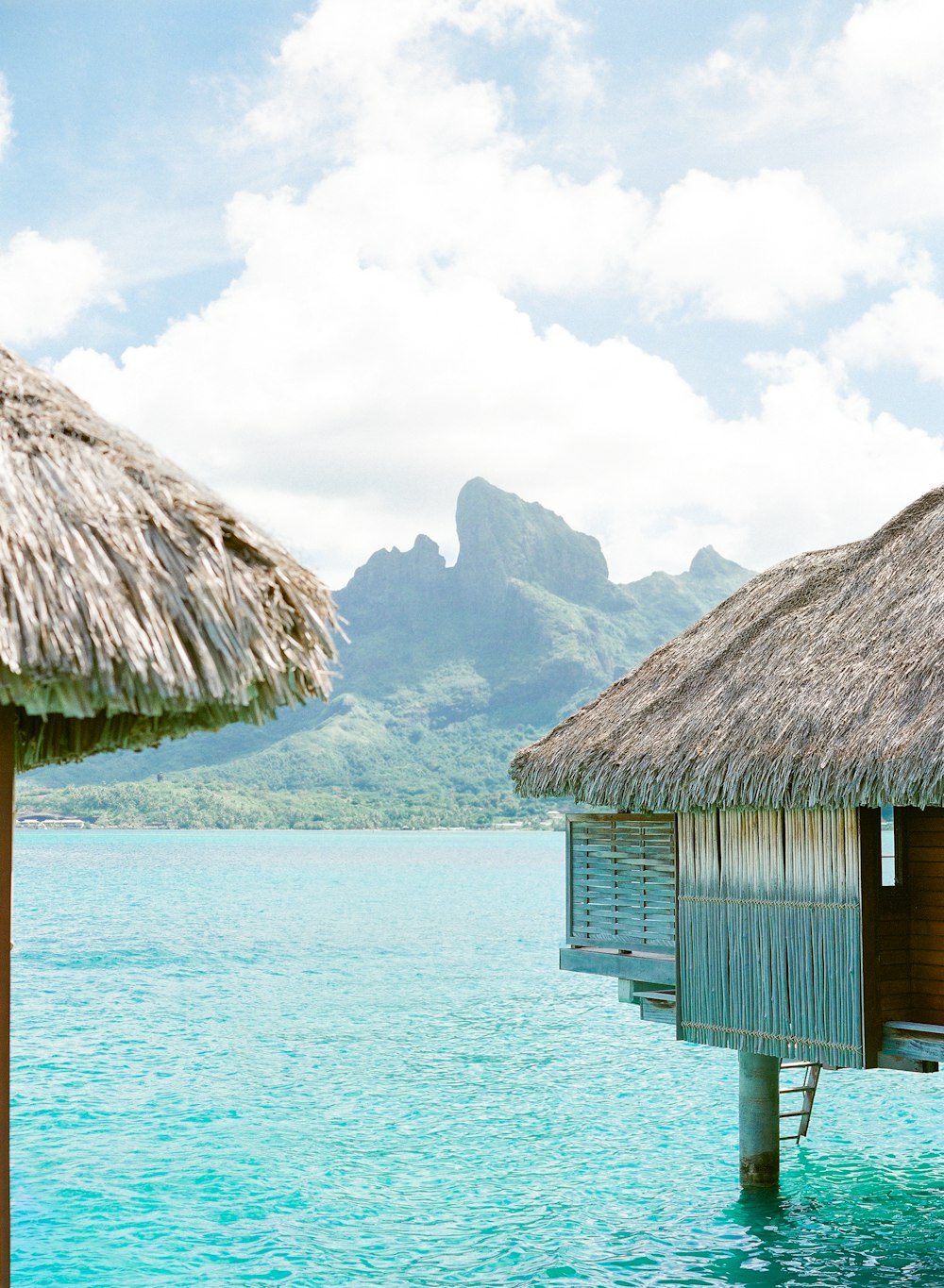 brown wooden house on body of water near mountain during daytime