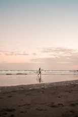 silhouette of man walking on beach during daytime