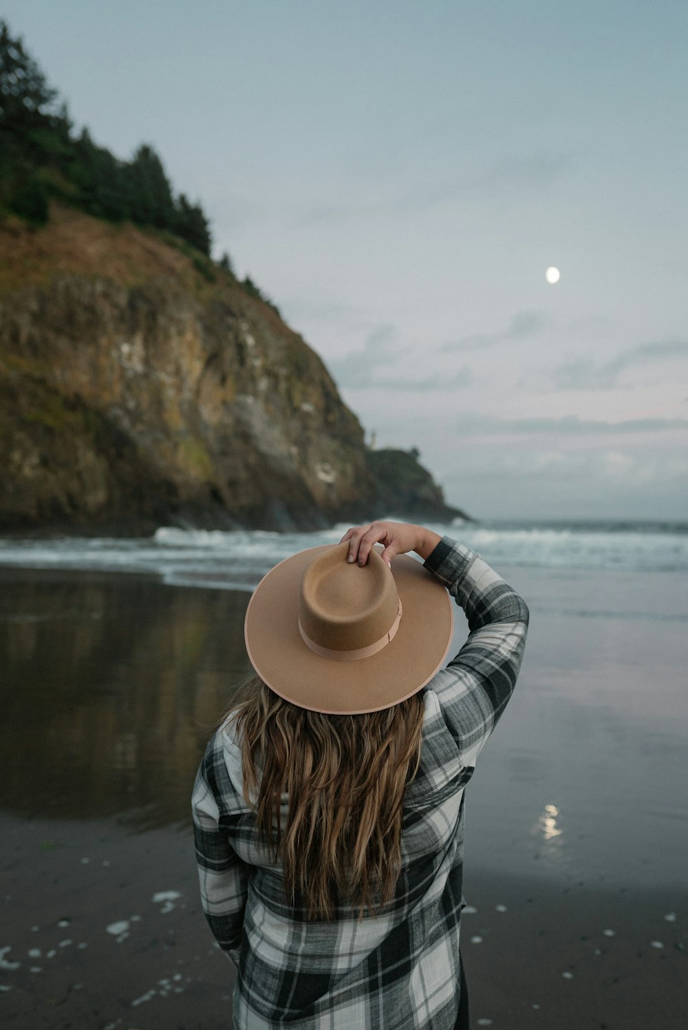 woman in blue and white plaid long sleeve shirt and beige hat standing near body of near on with near
