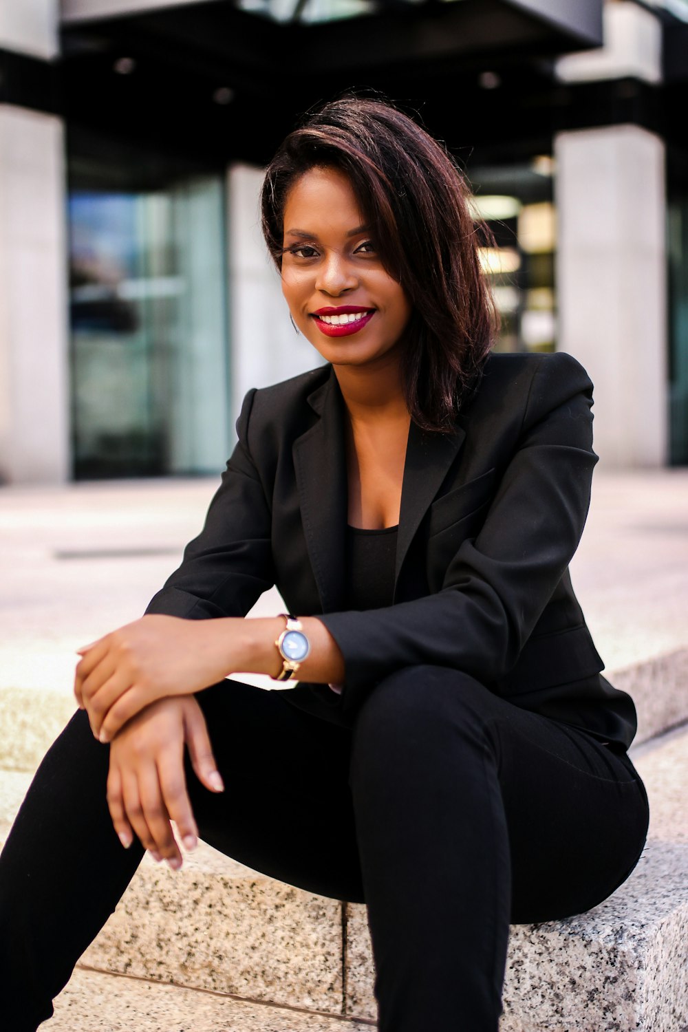 woman in black blazer sitting on concrete bench during daytime