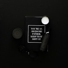 black framed eyeglasses beside white and black labeled bottle