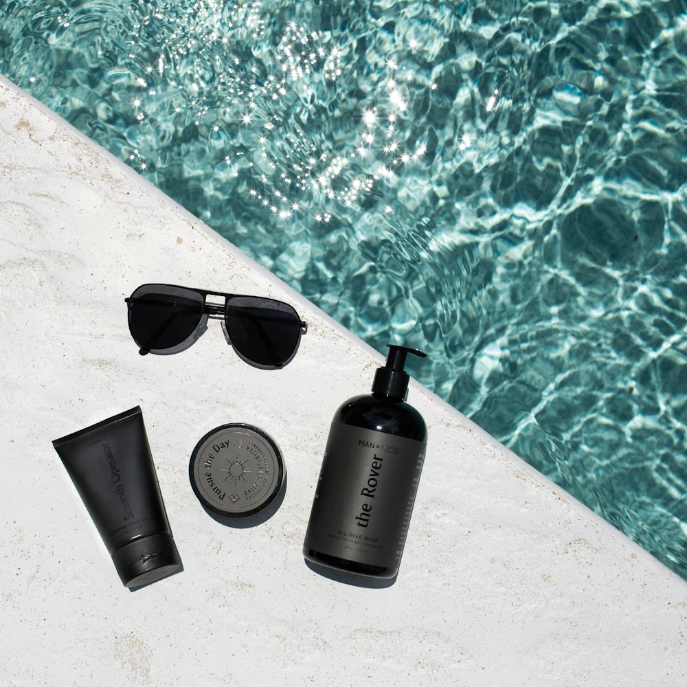 black and silver tube bottle beside black sunglasses