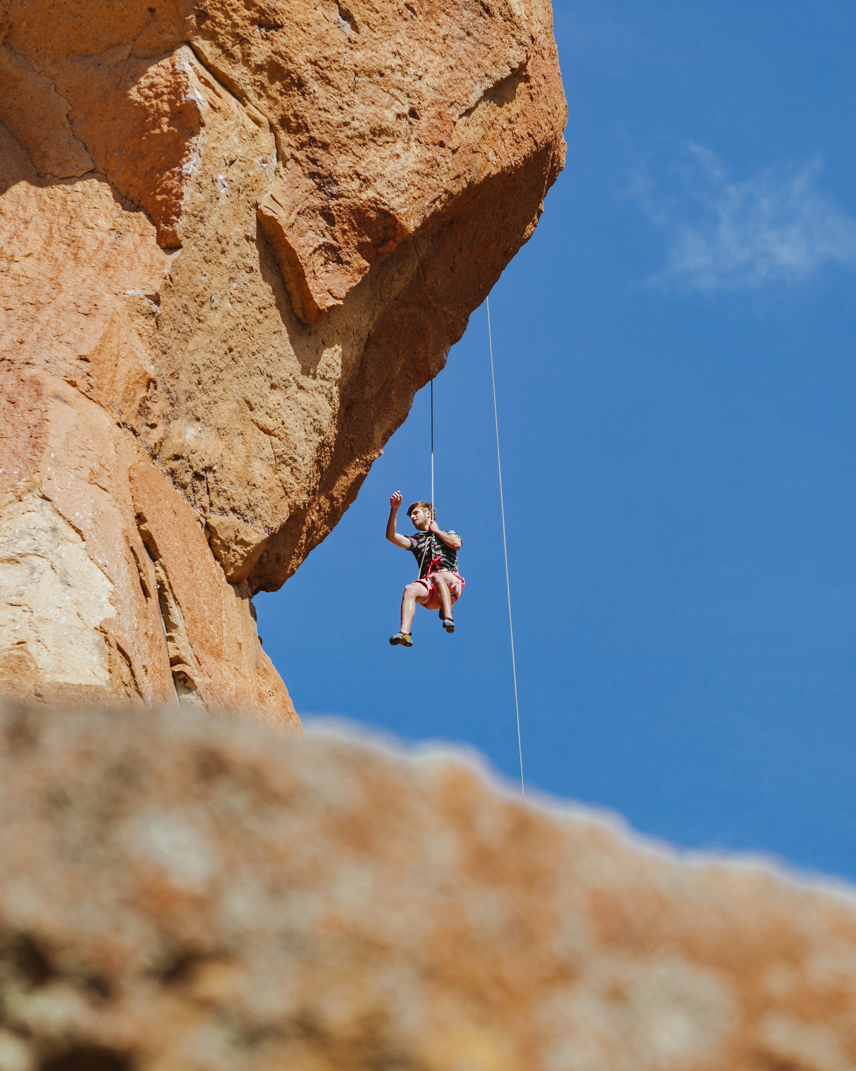 man in black shirt and black shorts jumping on brown rock during daytime