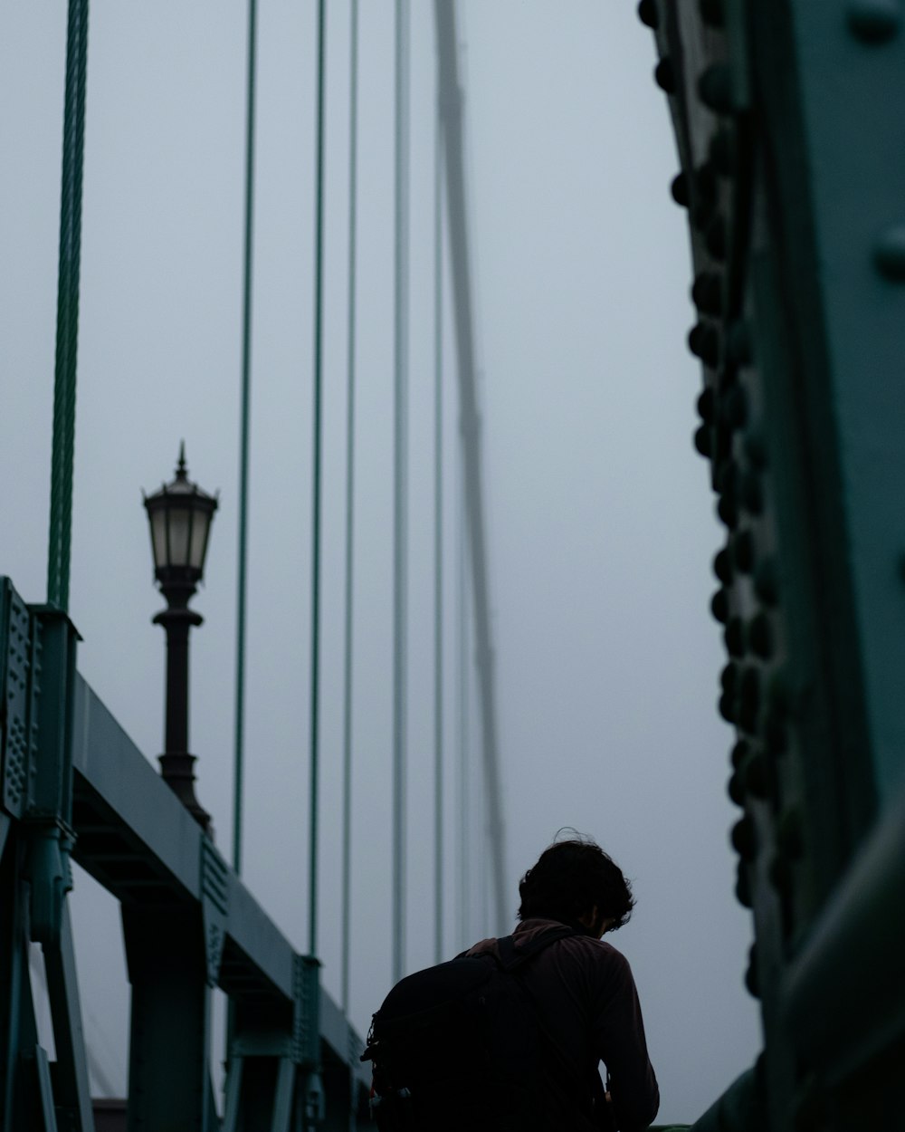 man in black jacket standing on bridge during daytime