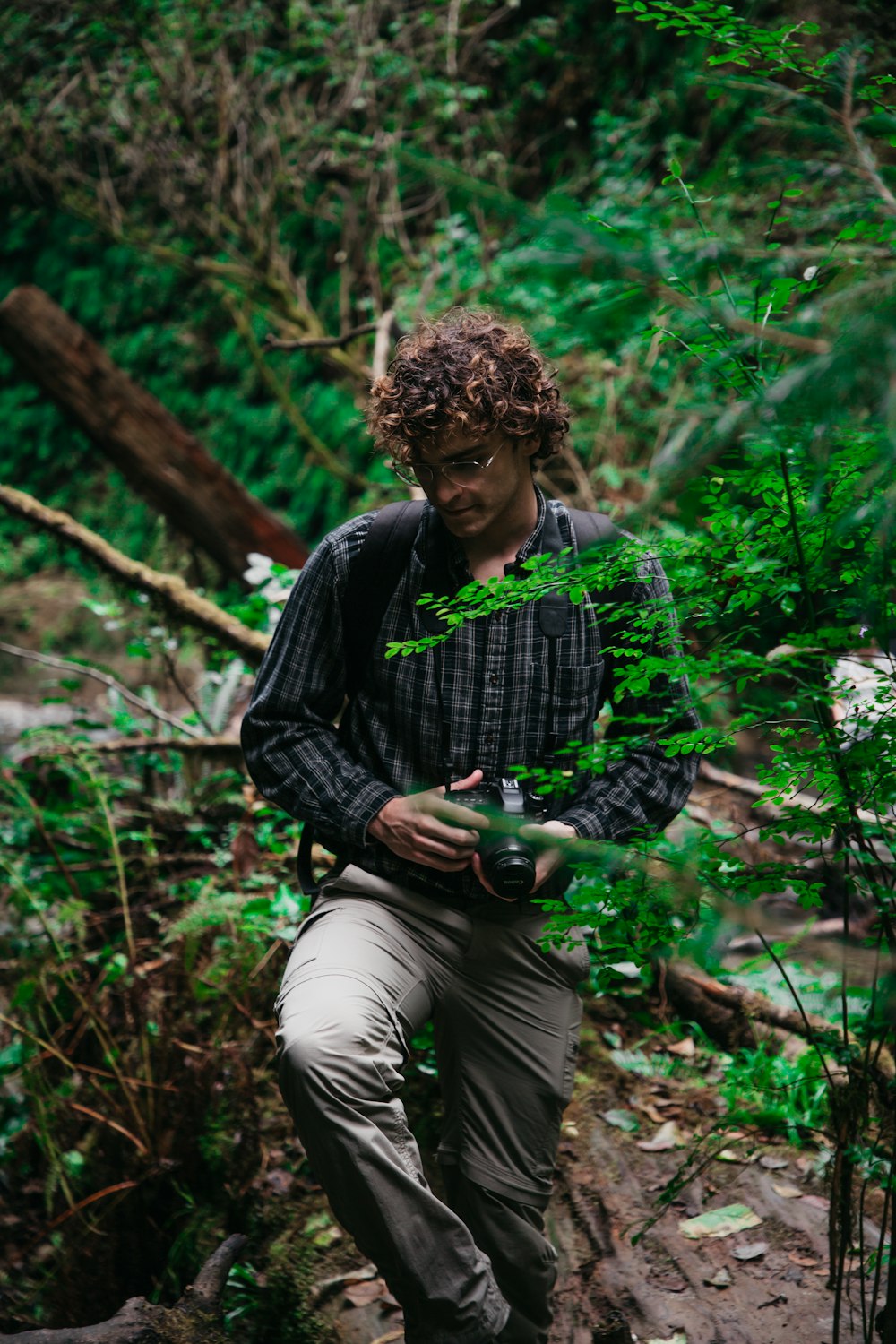 man in black and gray long sleeve shirt and gray pants sitting on brown tree log