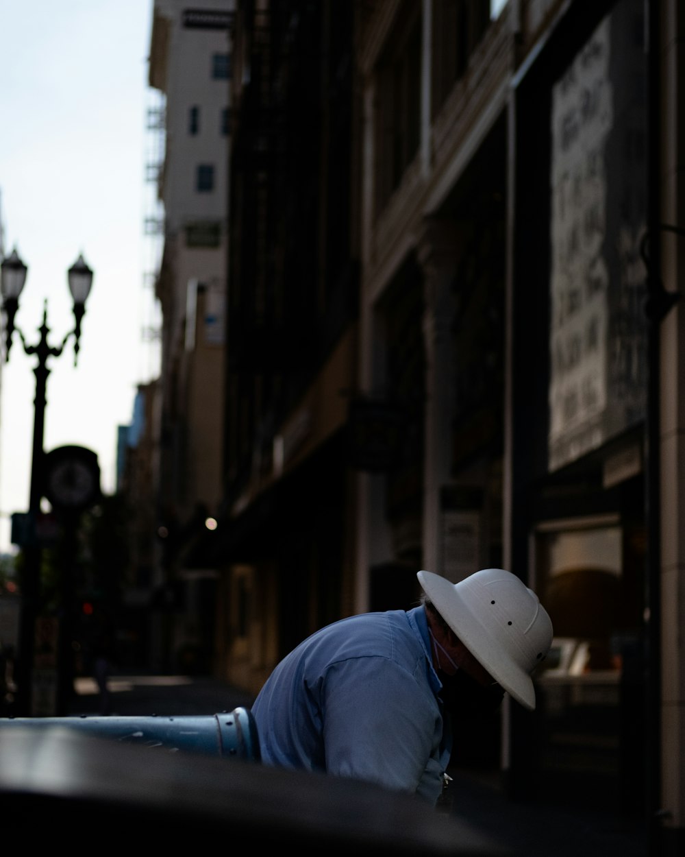 man in blue long sleeve shirt and white hat leaning on black metal railings