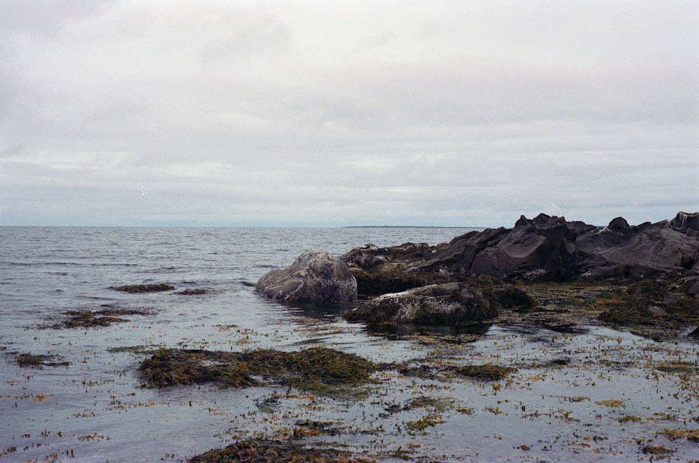 black rock formation on sea under white clouds during daytime