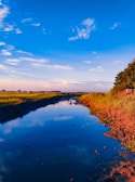 A serene landscape with a flowing river under a blue sky.