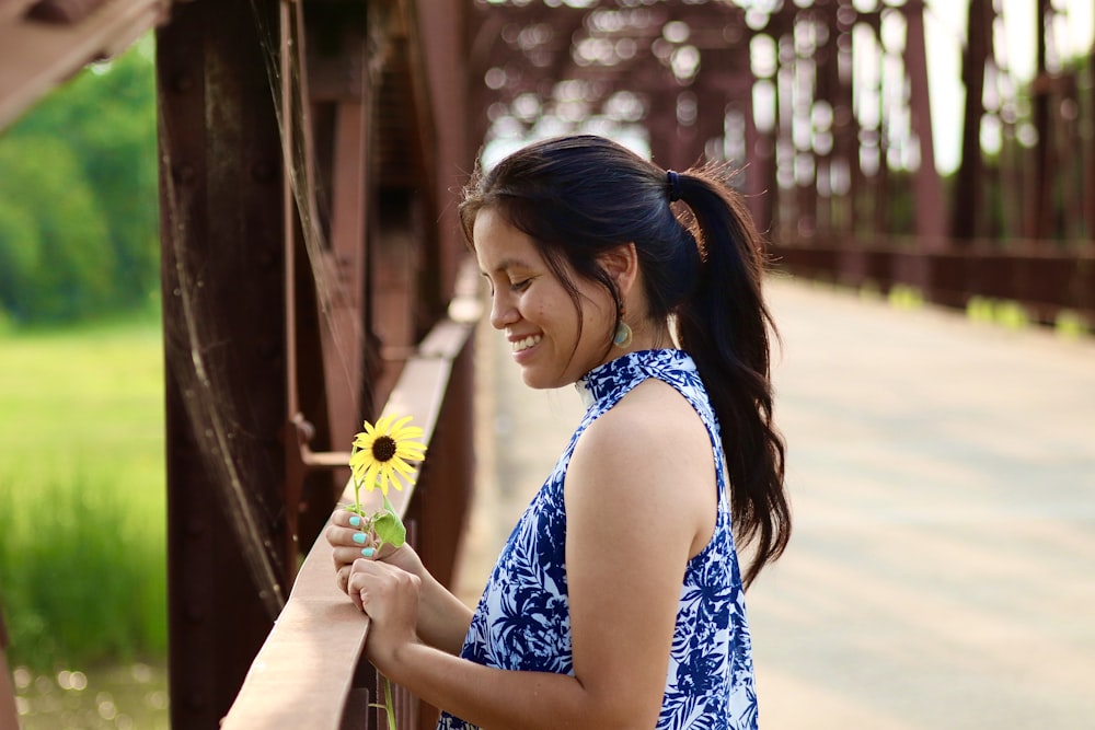 woman in blue and white floral sleeveless dress holding green plastic cup