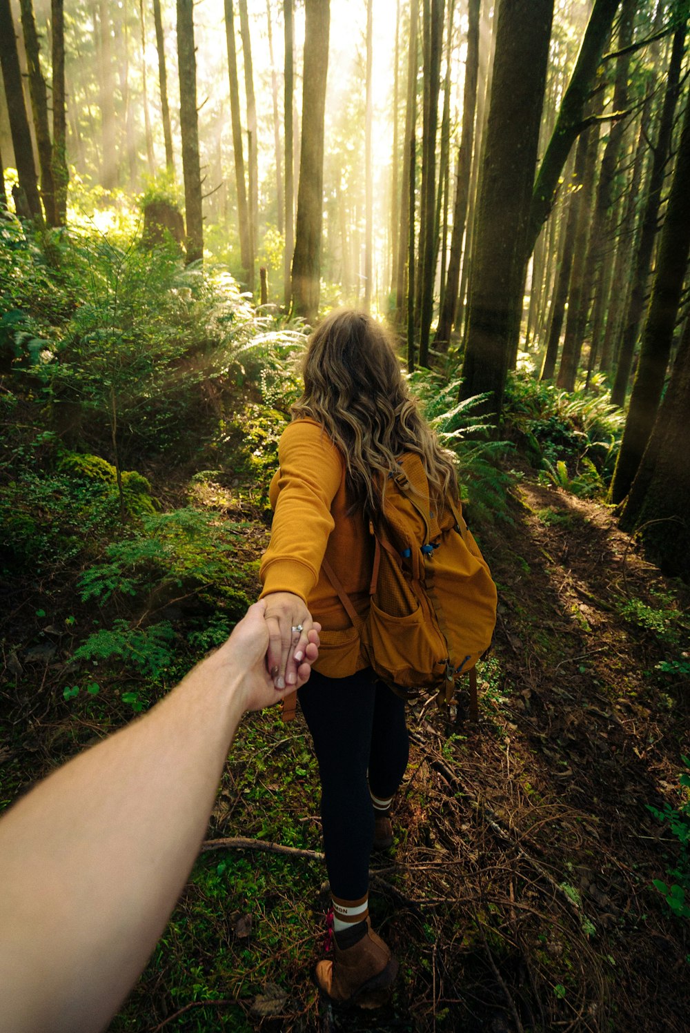 woman in brown jacket standing in forest during daytime