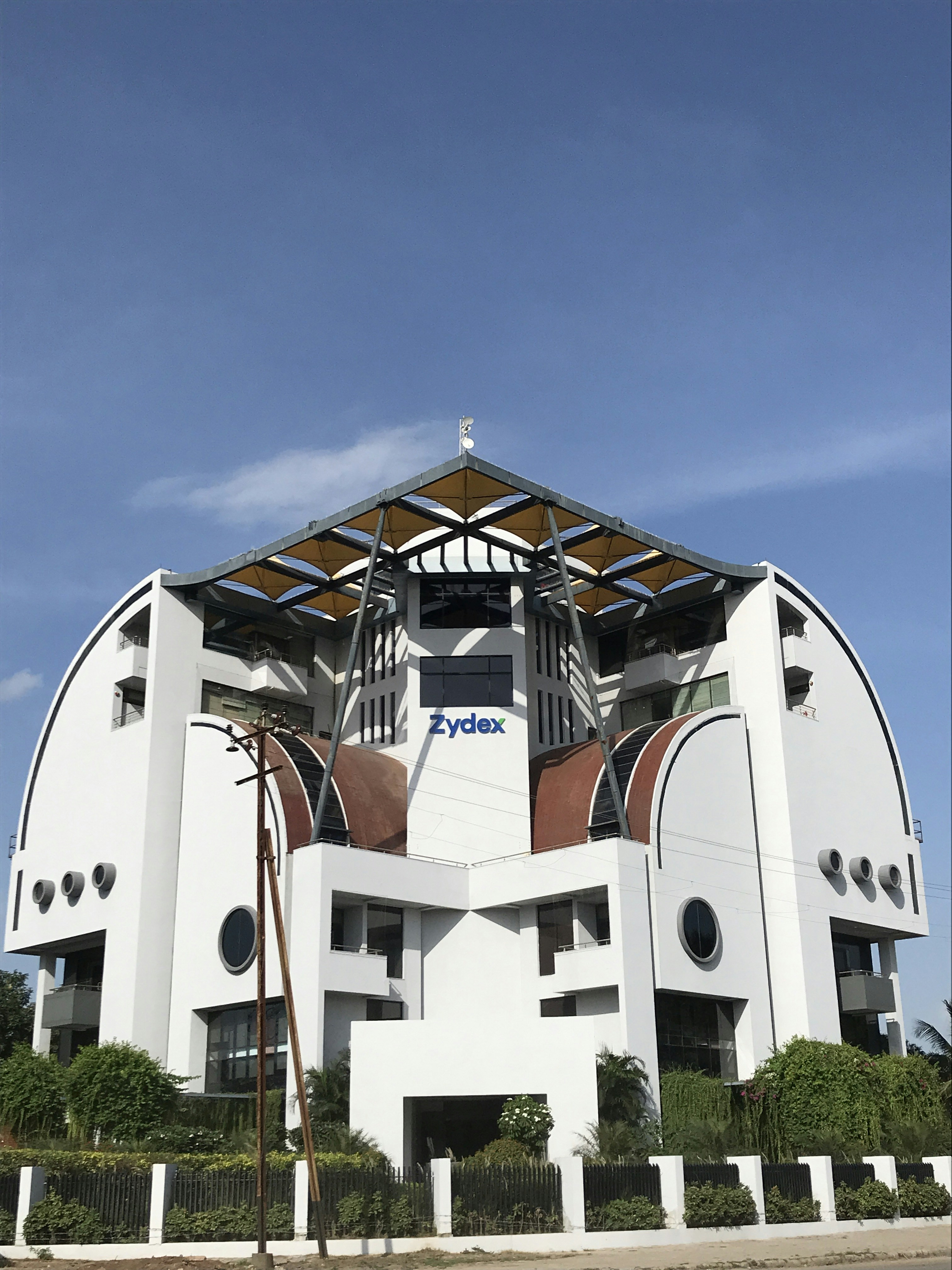 white concrete building with green trees under blue sky during daytime