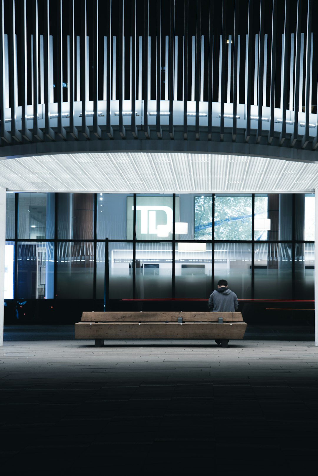 person sitting on bench near glass wall