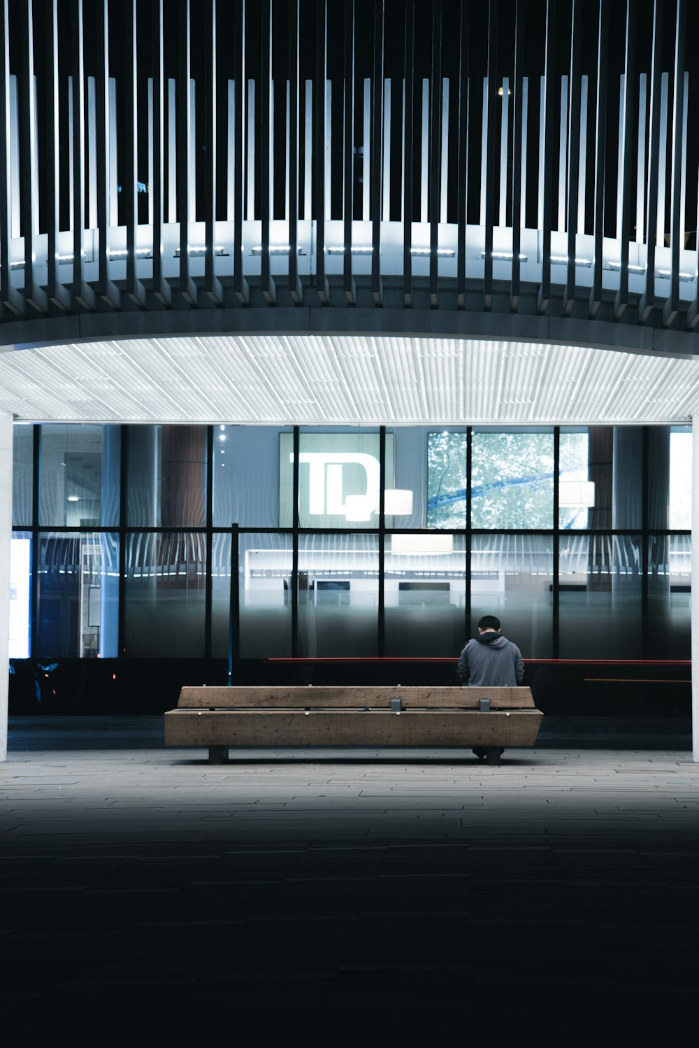 person sitting on bench near glass wall
