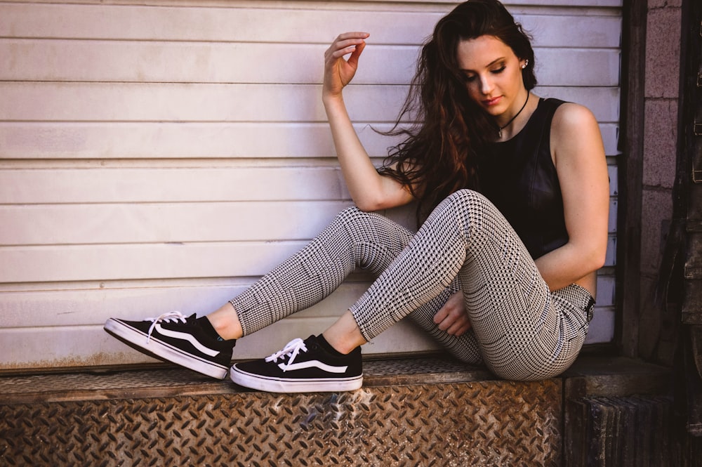 woman in black tank top and black and white striped pants sitting on brown carpet