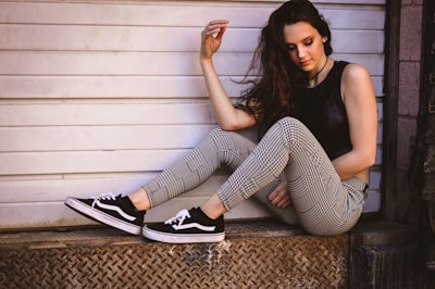 woman in black tank top and black and white striped pants sitting on brown carpet nebraska teams background
