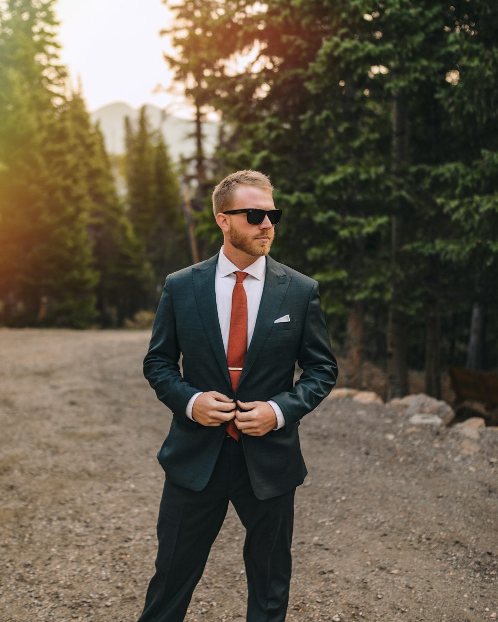 man in black suit standing on dirt ground during daytime