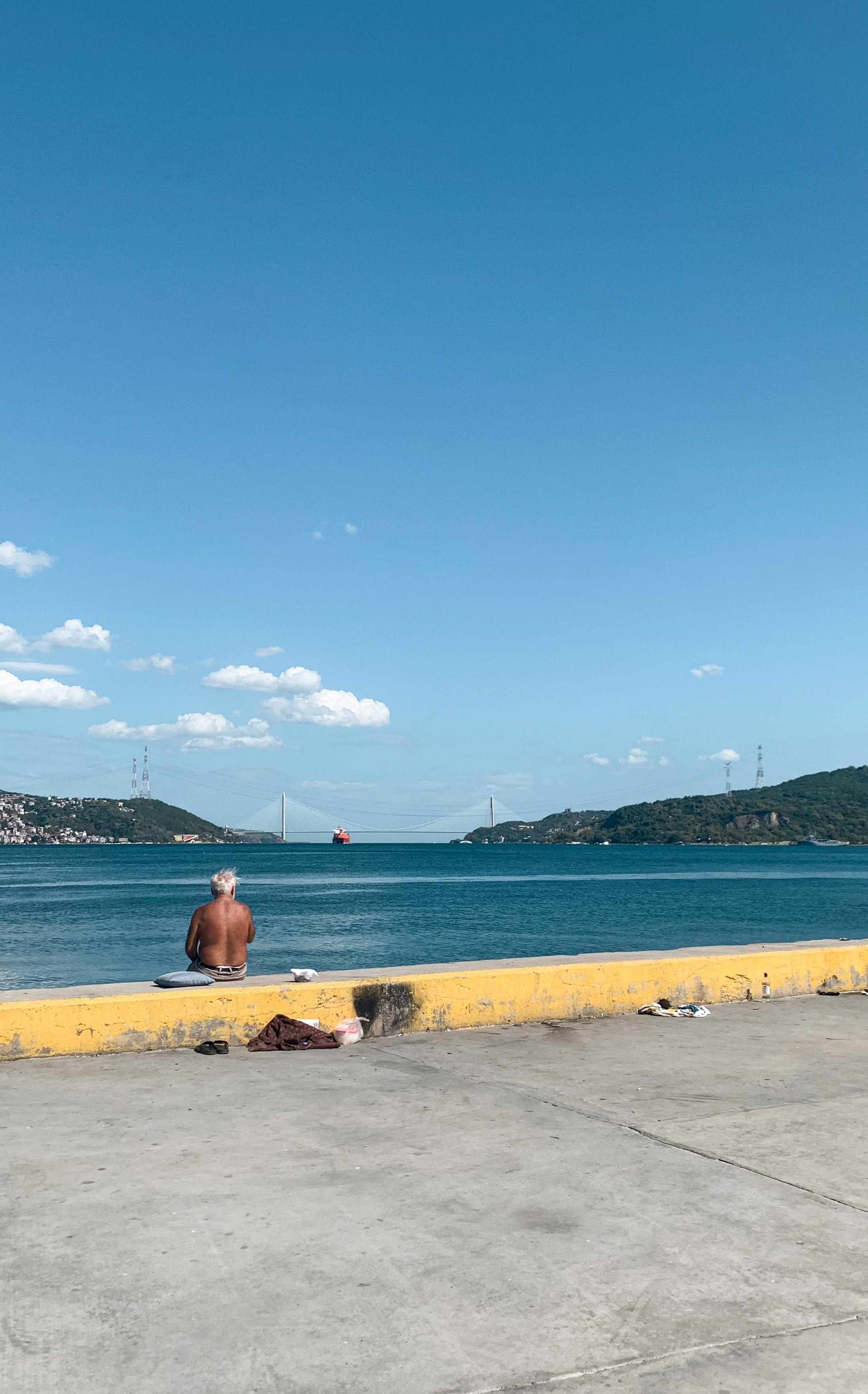 A man sitting by the water, about to jump in to swim. 