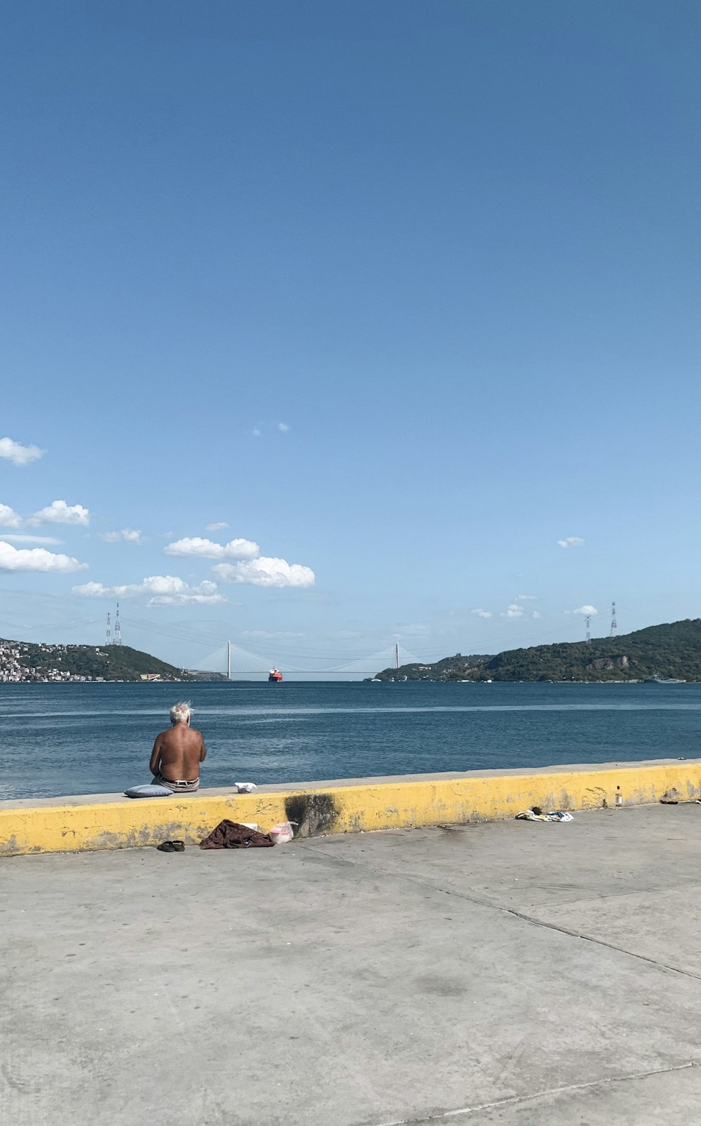 woman in red dress sitting on brown concrete bench near body of water during daytime