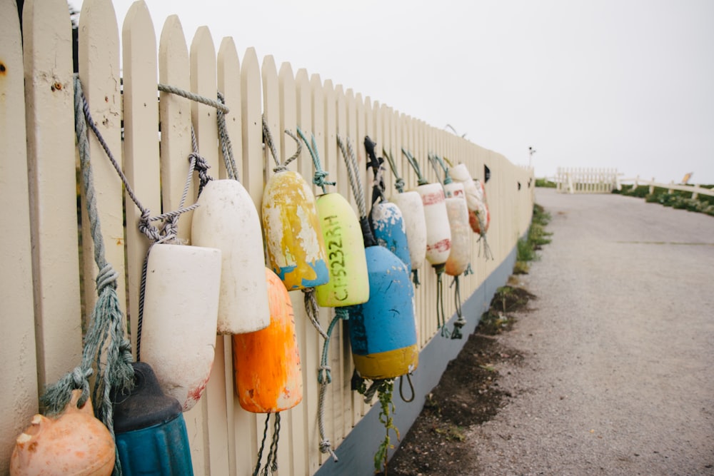 yellow and blue plastic container hanged on white wooden fence during daytime