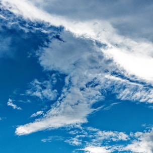 A dramatic sky with deep blue tones and volumetric clouds over a vibrant foreground.