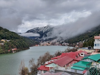 houses near lake and mountain during daytime
