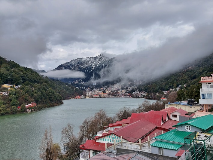 houses near lake and mountain during daytime