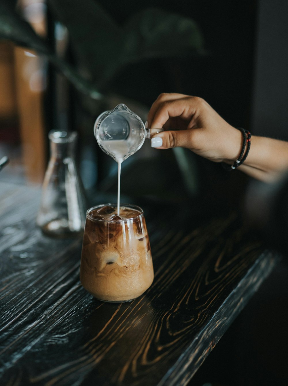 person pouring brown liquid on clear wine glass