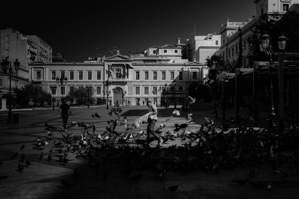 grayscale photo of people walking on street near building