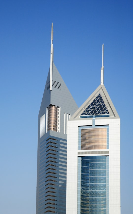 white and brown concrete building under blue sky during daytime in Emirates Towers United Arab Emirates