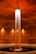 A cylindrical room featuring a central column of water illuminated dramatically from above. The water cascades into a circular pool surrounded by concrete walls. Warm lighting accentuates the reddish-brown tones of the space, adding a serene and mysterious atmosphere.