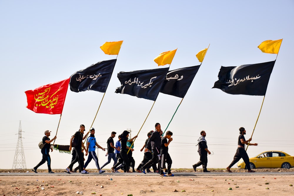 personnes debout sur du sable brun avec des drapeaux pendant la journée