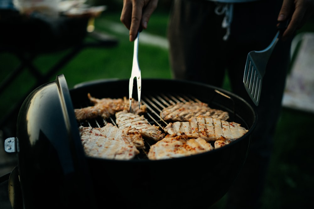 personne tenant une fourchette et un couteau en train de trancher de la viande