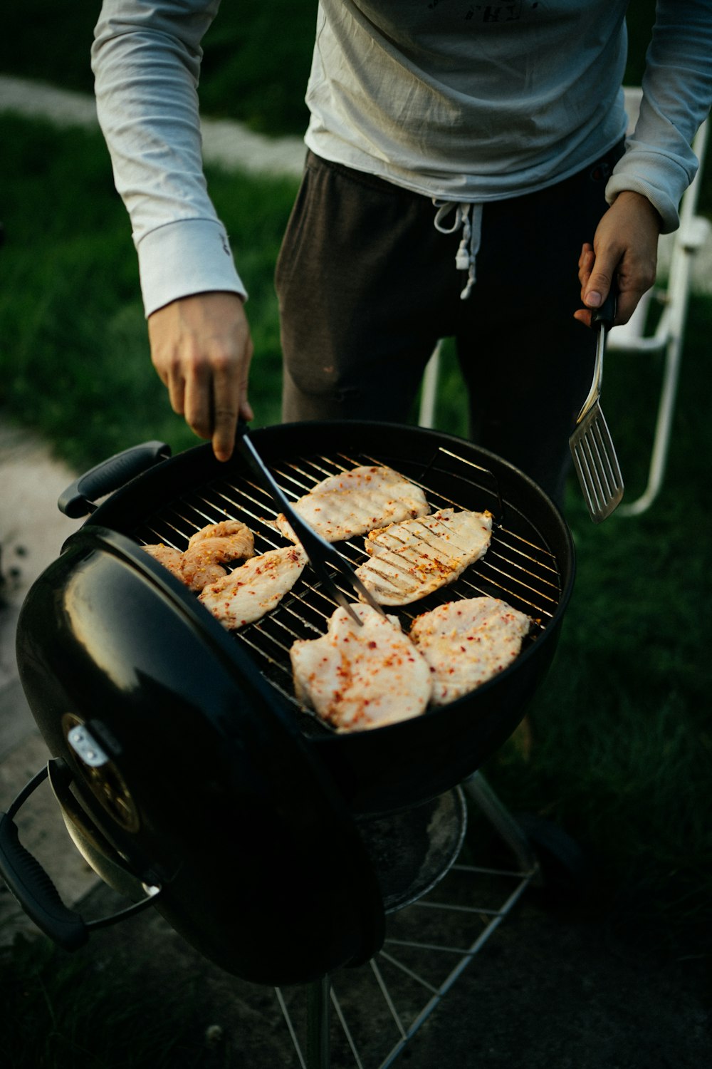 person holding black kettle grill with meat