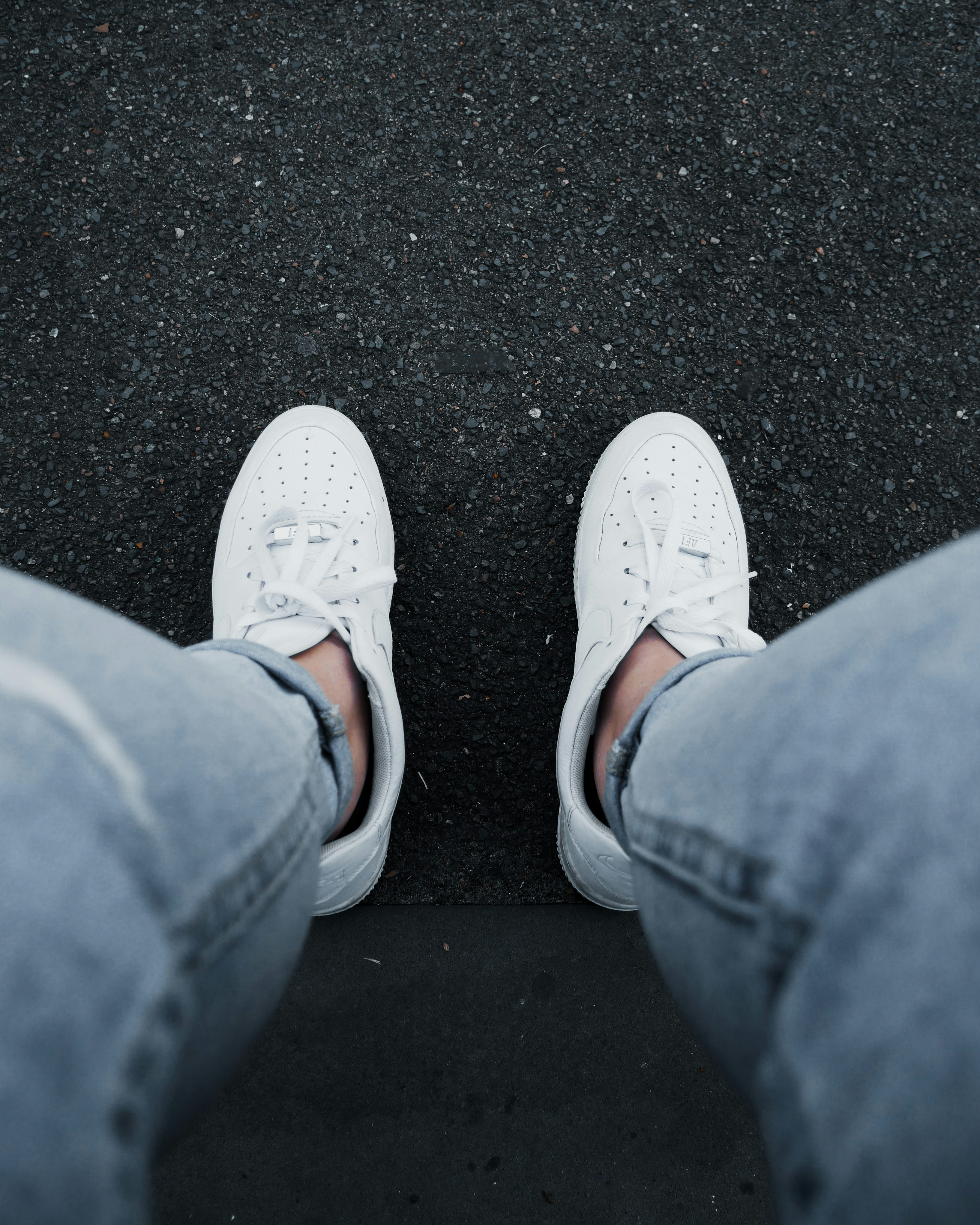 person in blue denim jeans and white sneakers