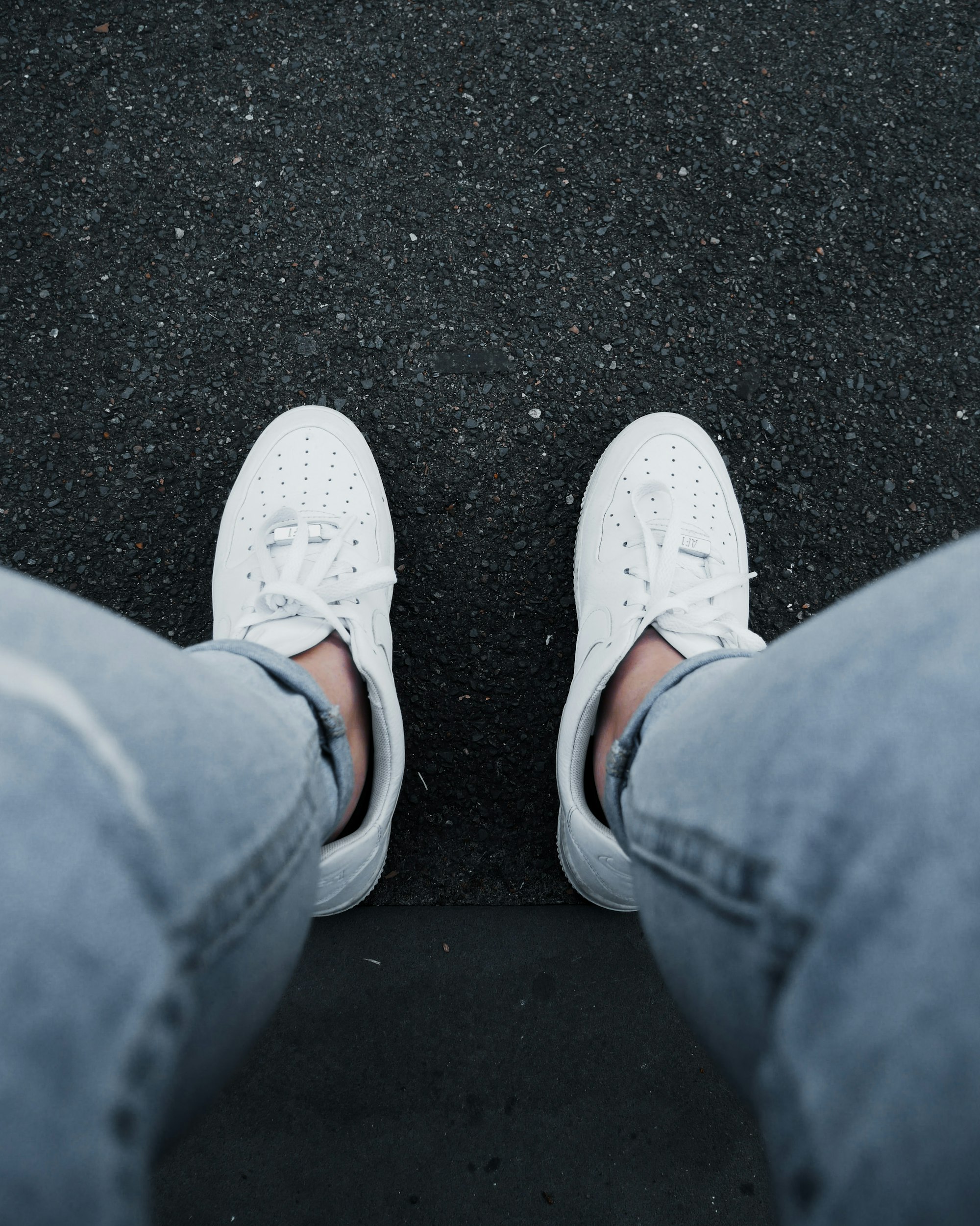 person in blue denim jeans and white sneakers