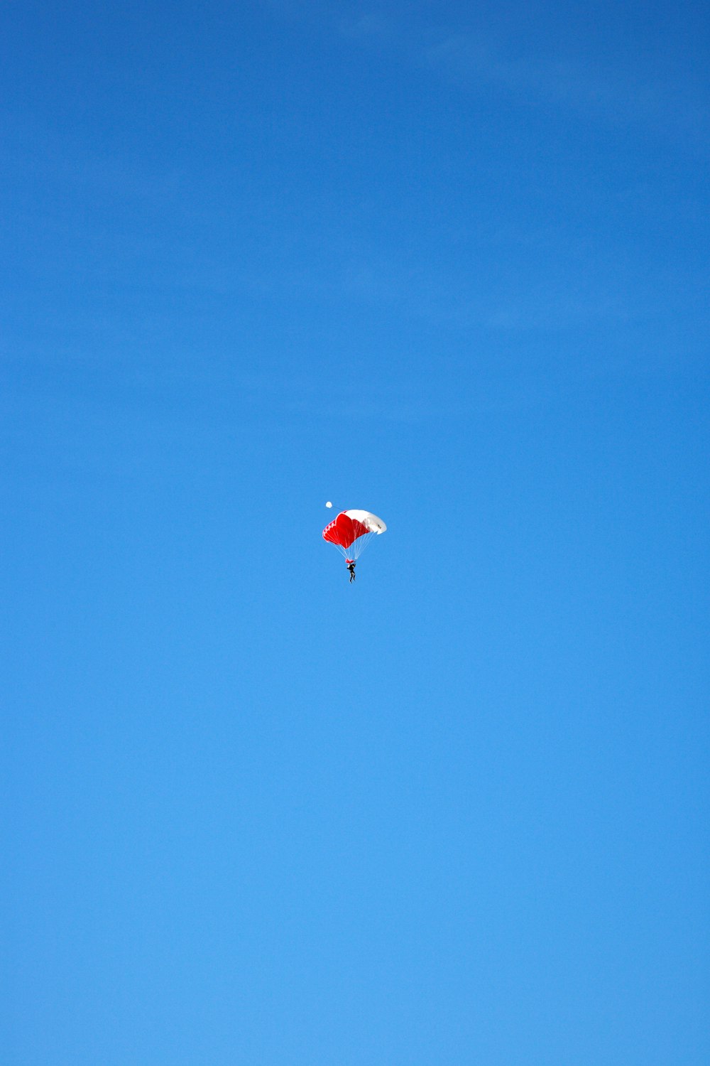 person in red parachute in mid air during daytime