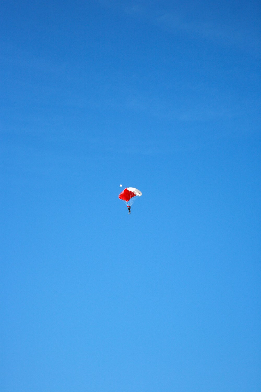 Persona en paracaídas rojo en el aire durante el día