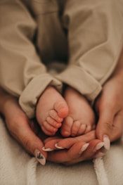 baby in white blanket on persons lap