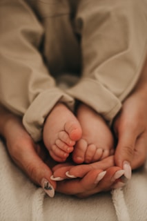 baby in white blanket on persons lap