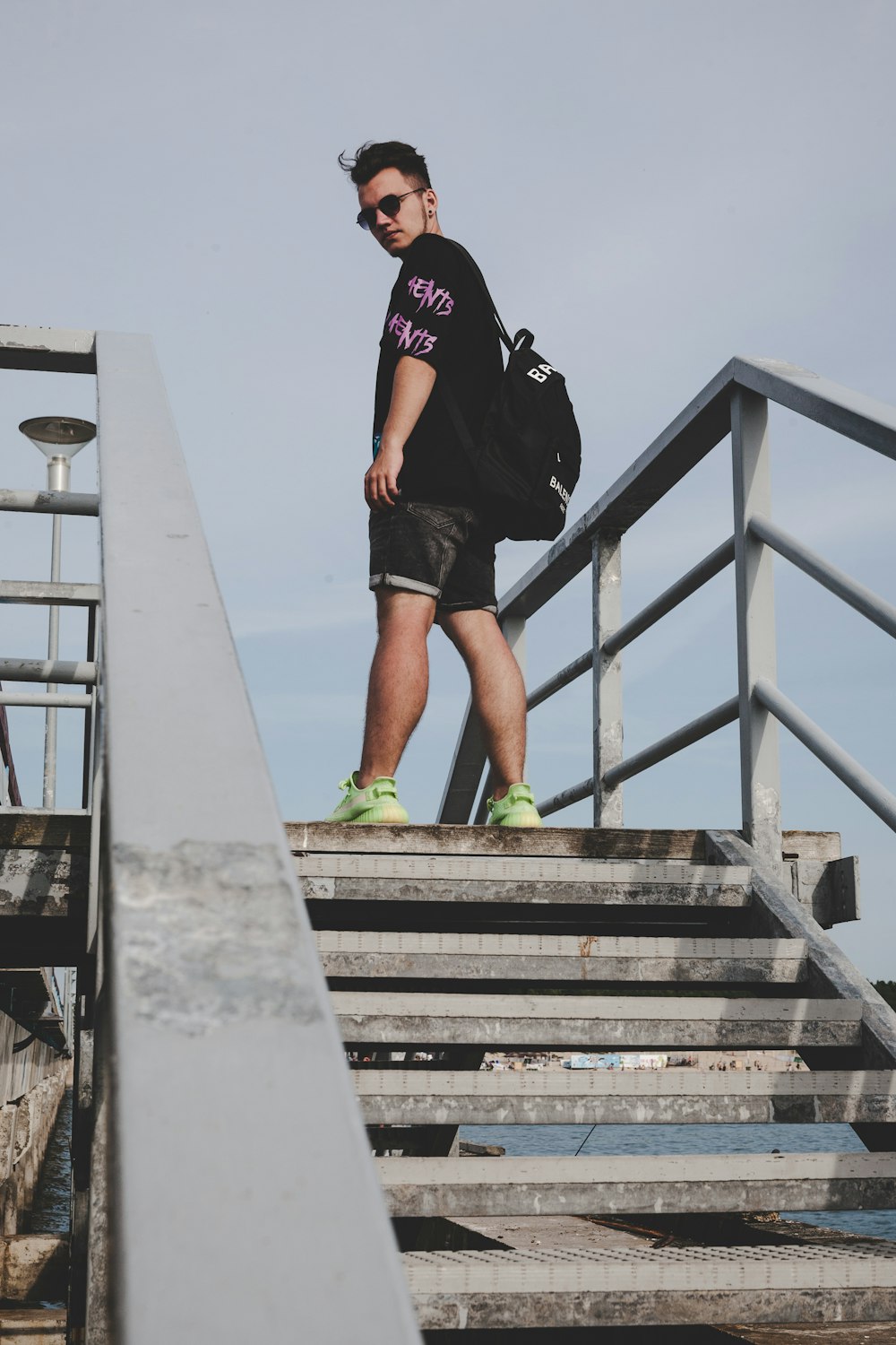 man in black t-shirt and black shorts standing on gray concrete staircase