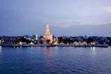 The serene Wat Arun temple glowing softly at sunset by the river.